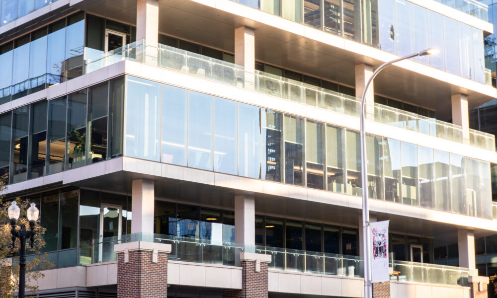 SpaceCo, glass wall building with pillars, across street, blurred white car, google headquarters